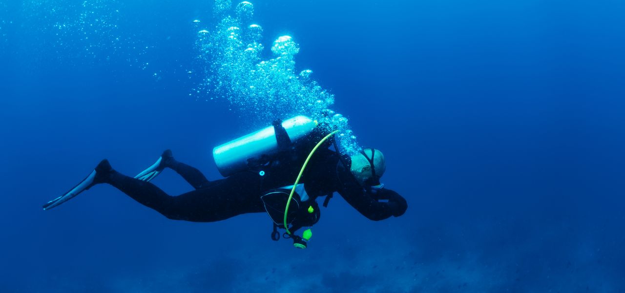 Certified instructor teaching scuba diving techniques to students in clear blue water during a beginner diving course