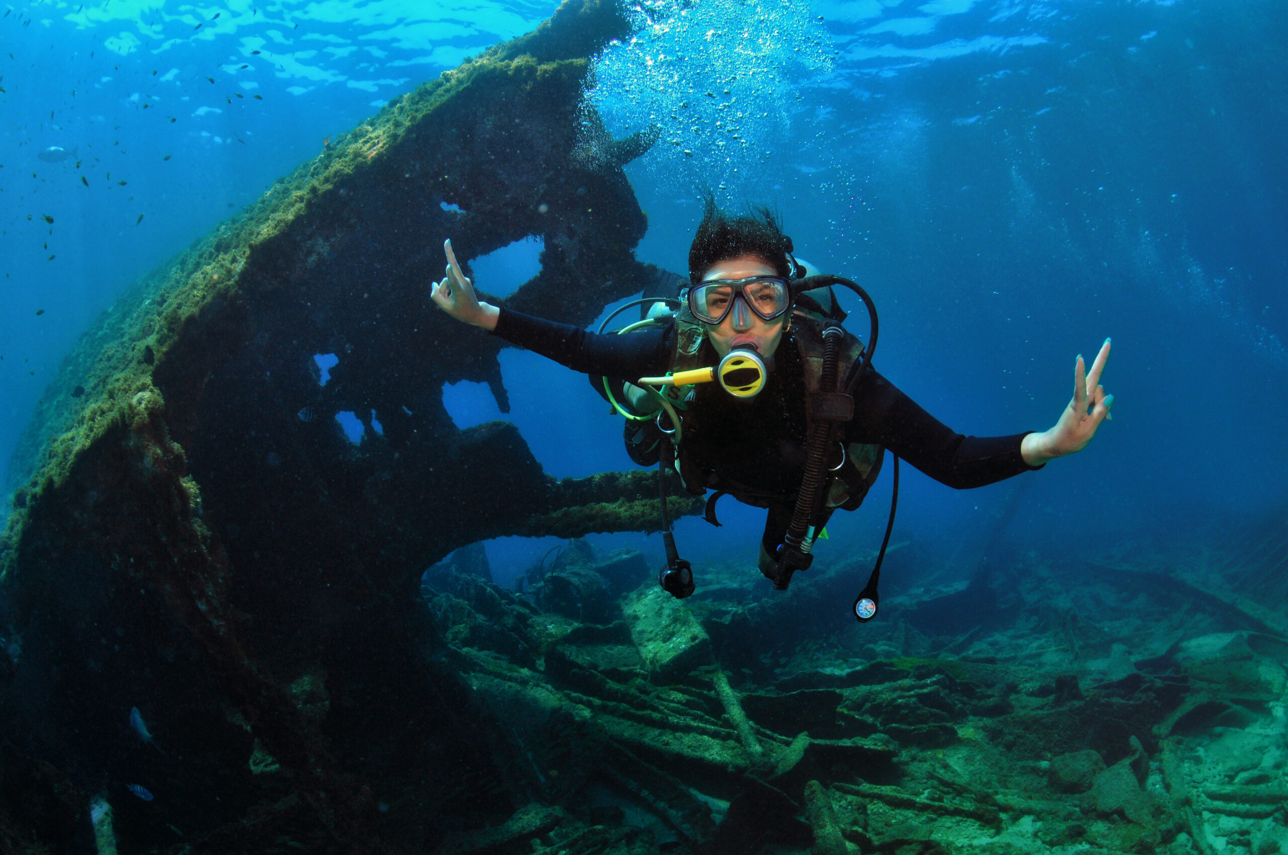 woman doing scuba diving near shipwreck